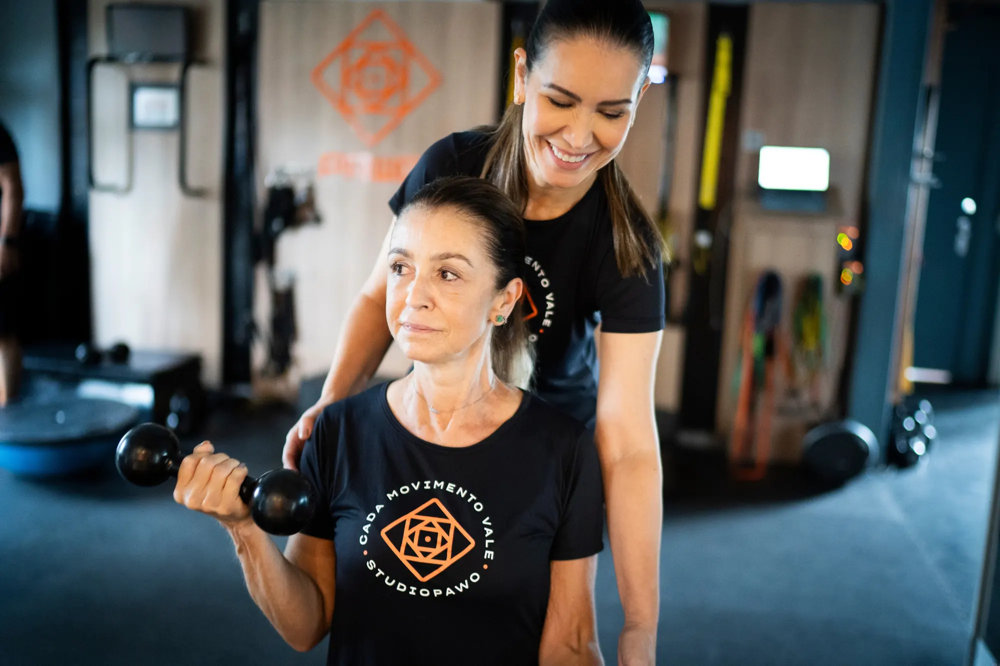 Professora acompanha uma aluna em um exercício com halter no Studio Pawo
