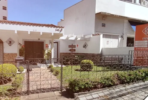 Fachada da unidade Batel, uma casa com jardim e portão de ferro